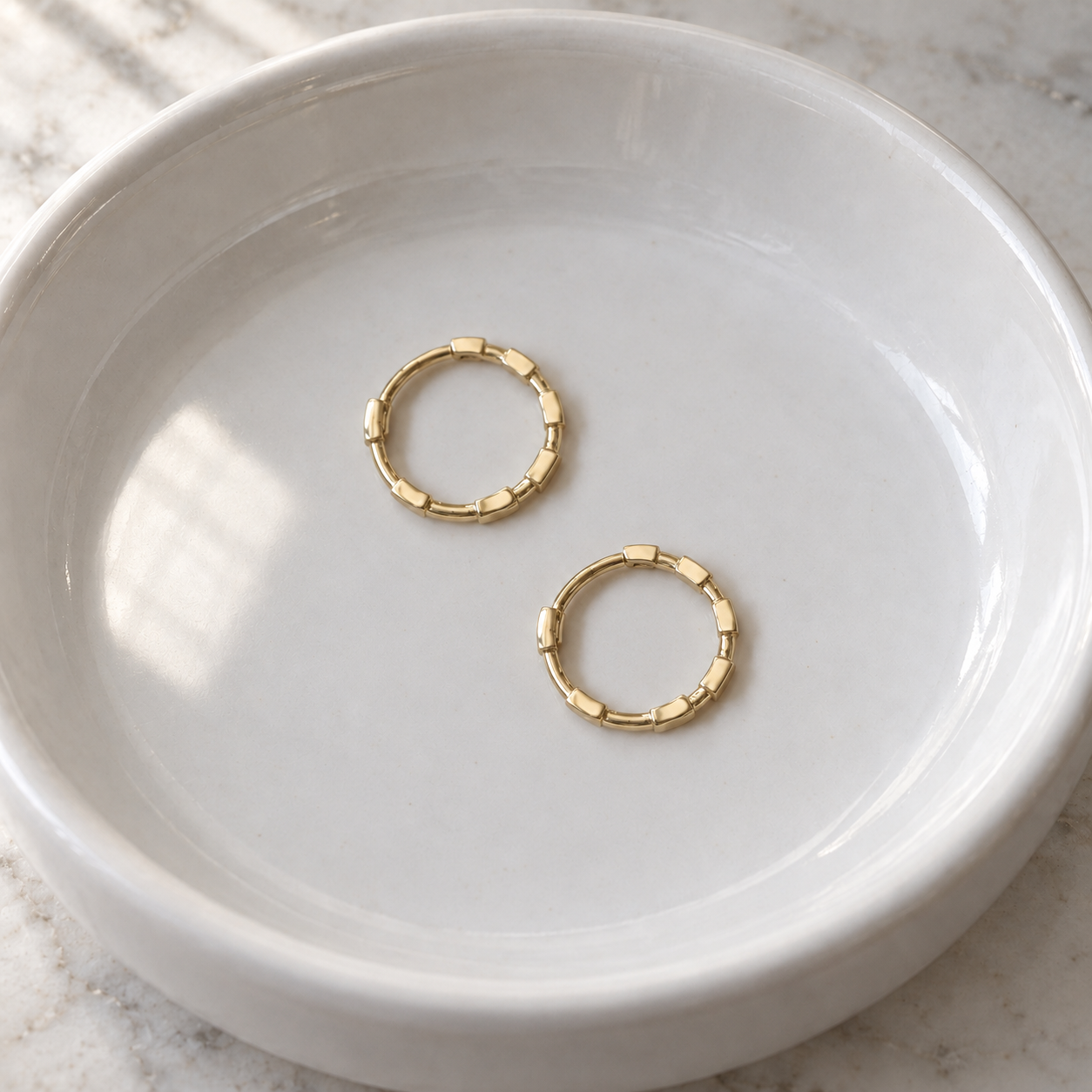 Pair of closed Cora Bamboo Hoops resting in a white ceramic basin