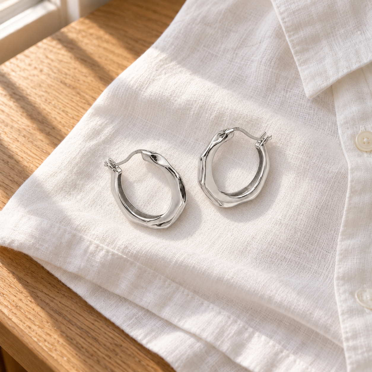 Mabel Sculpted Hoops resting on white linen; styling props not included