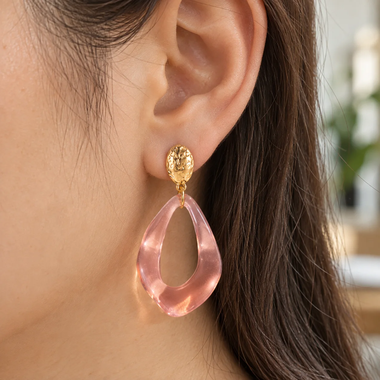 Pink transparent open teardrop earrings with textured gold oval studs: use view; other styling items not included