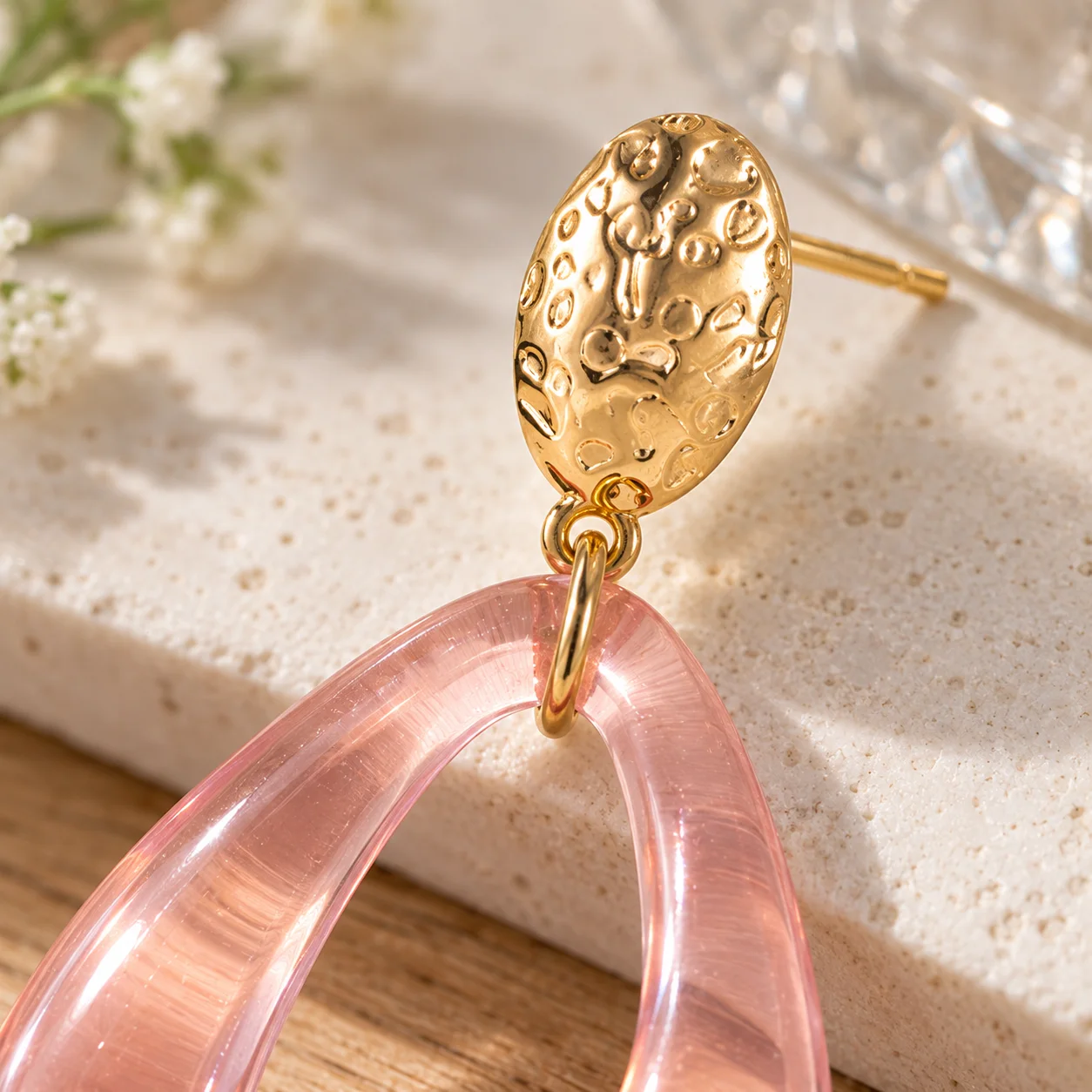 Pink transparent open teardrop earrings with textured gold oval studs: detail view; other styling items not included