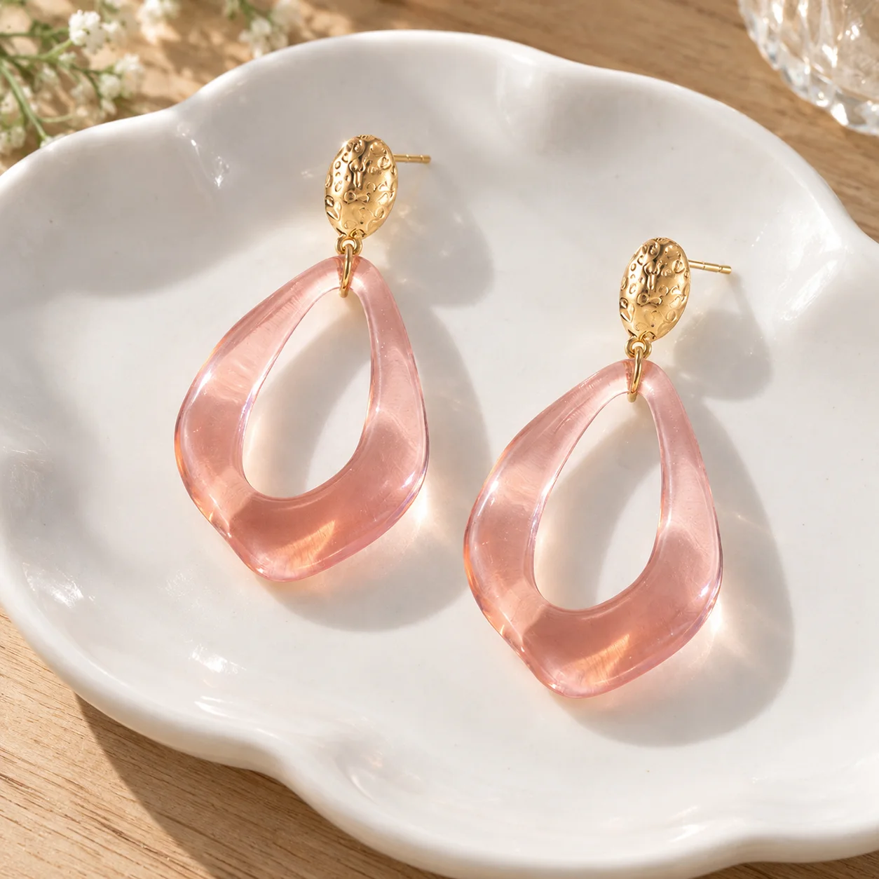 Pink transparent open teardrop earrings with textured gold oval studs: lead view; other styling items not included